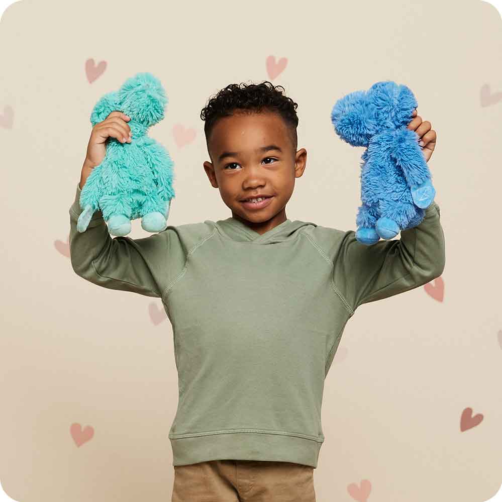 Image 101: Boy raising his hands and holding Cute Weighted Lavender Scented Dinosaur Hugs Stuffed Animal Heating Pad Warmies